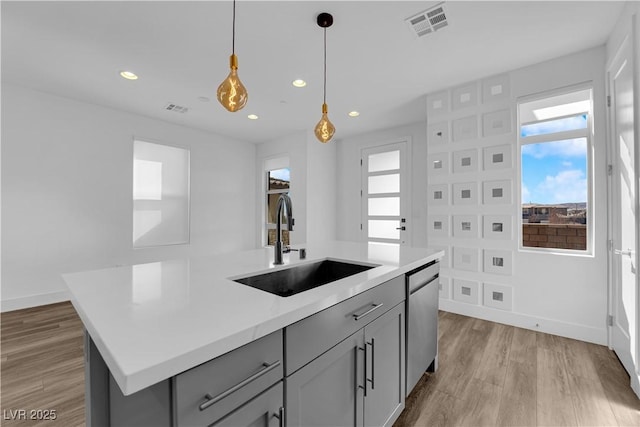 kitchen with sink, gray cabinetry, decorative light fixtures, dishwasher, and a kitchen island with sink