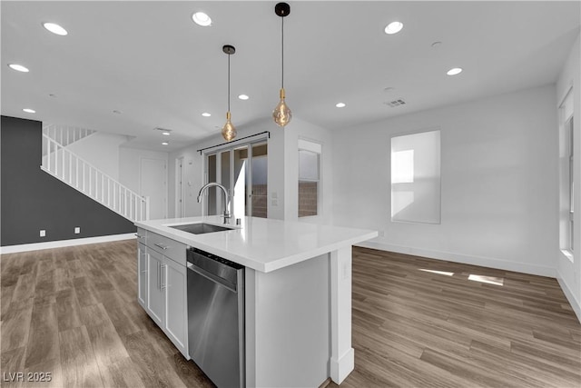 kitchen with decorative light fixtures, white cabinetry, sink, stainless steel dishwasher, and a center island with sink