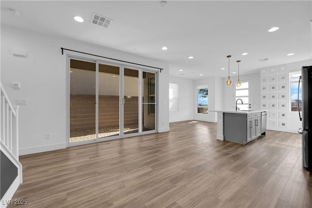 unfurnished living room featuring sink and light wood-type flooring