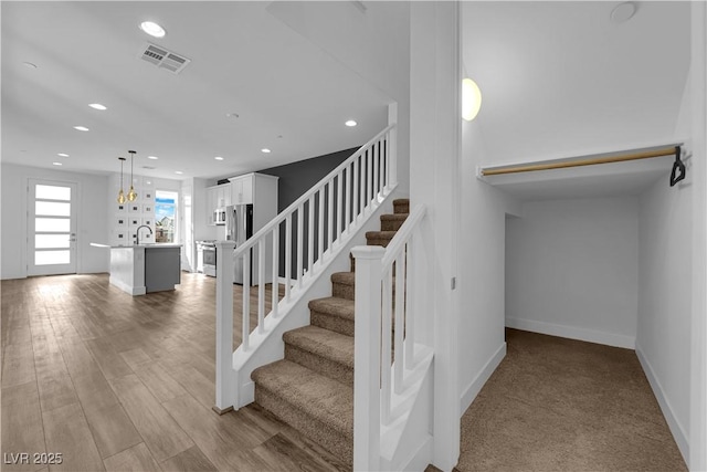 stairs featuring wood-type flooring and sink