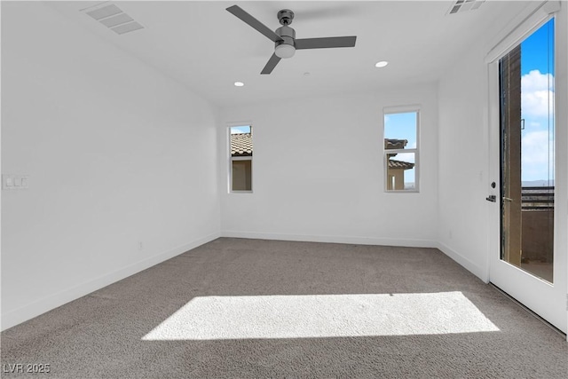 spare room with plenty of natural light, light colored carpet, and ceiling fan