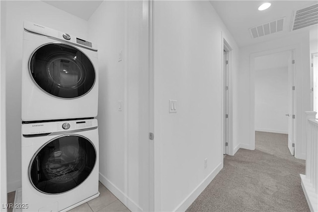 laundry area with light carpet and stacked washer / drying machine