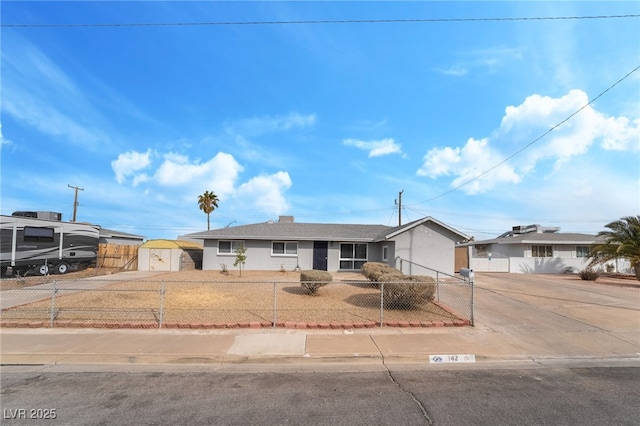 ranch-style home featuring concrete driveway, a fenced front yard, and stucco siding