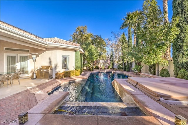 view of pool with area for grilling, a patio area, and a jacuzzi