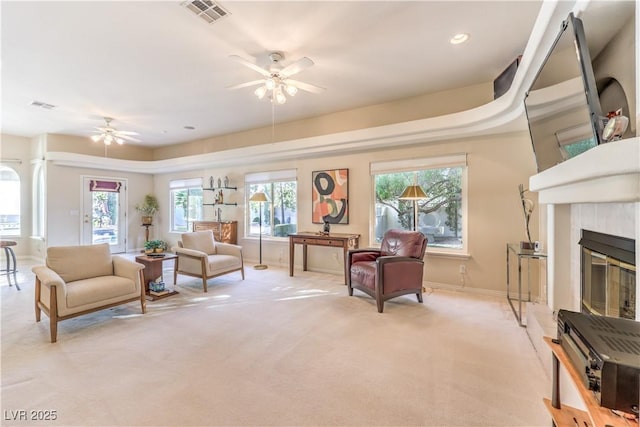 living room with light carpet, a wealth of natural light, a fireplace, and ceiling fan