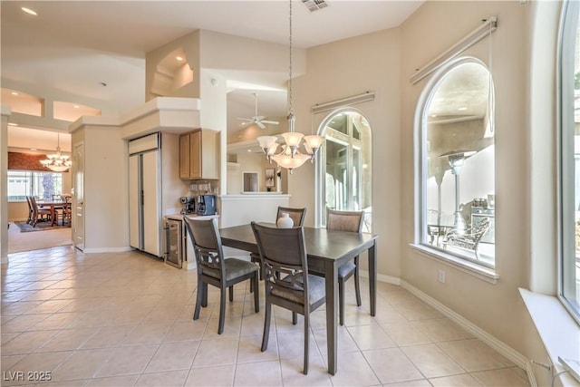 tiled dining space with ceiling fan with notable chandelier