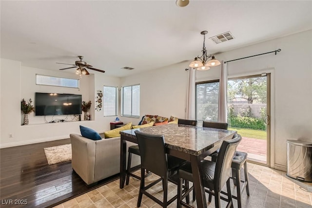 dining area with ceiling fan with notable chandelier, a healthy amount of sunlight, and light wood-type flooring