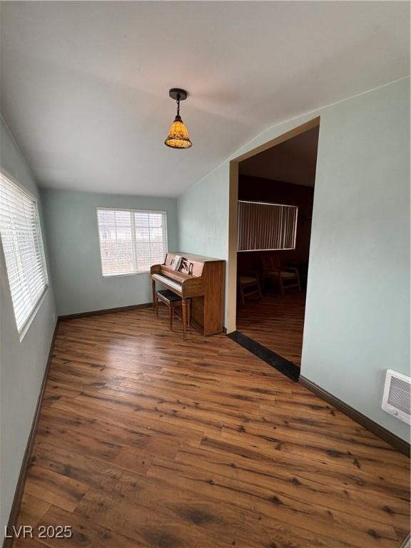 spare room featuring lofted ceiling and dark hardwood / wood-style floors