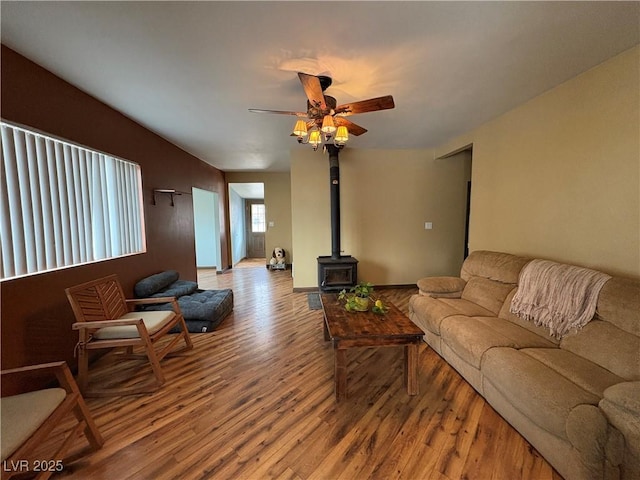 living room with ceiling fan, light wood-type flooring, and a wood stove