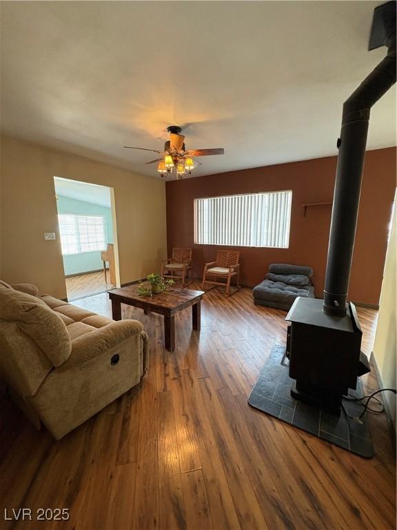 living room featuring hardwood / wood-style floors, ceiling fan, and a wood stove