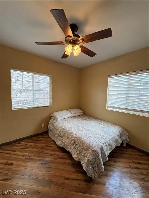 bedroom featuring ceiling fan, dark hardwood / wood-style flooring, and multiple windows