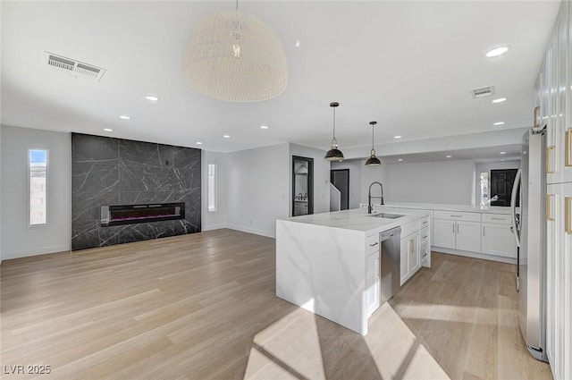 kitchen featuring sink, appliances with stainless steel finishes, pendant lighting, light stone countertops, and white cabinets