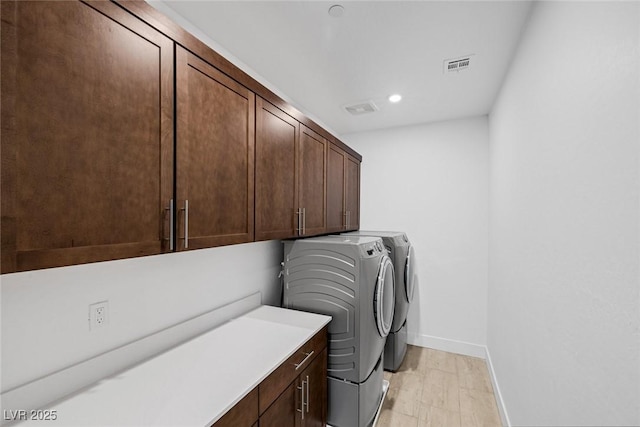 laundry area featuring independent washer and dryer, cabinets, and light wood-type flooring