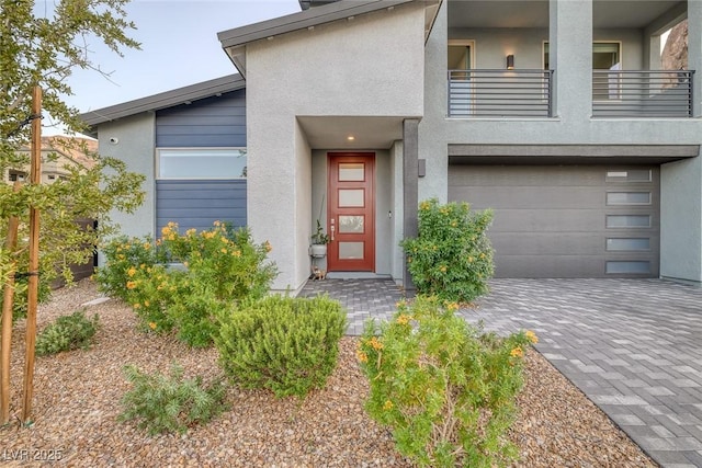 view of exterior entry with a garage and a balcony