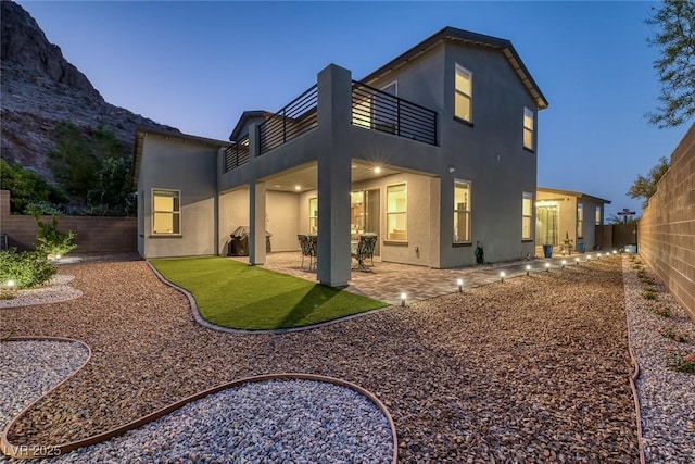 back house at dusk with a patio