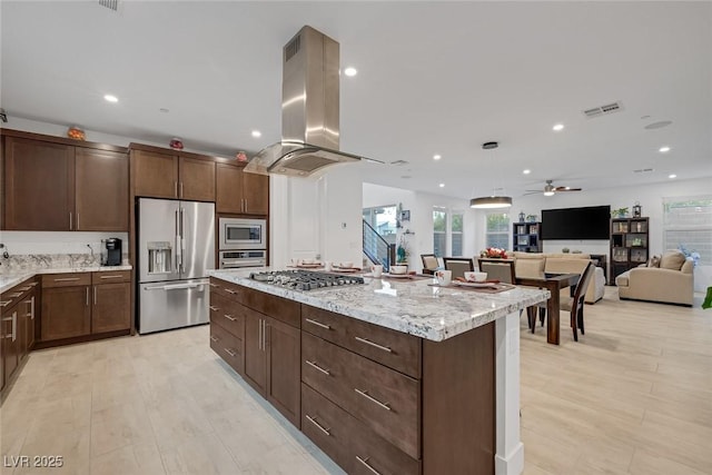 kitchen featuring light stone counters, island range hood, a center island, ceiling fan, and stainless steel appliances