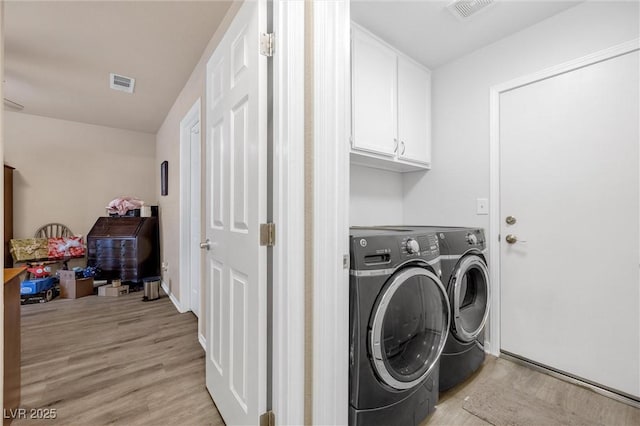 laundry area with cabinets, washing machine and clothes dryer, and light hardwood / wood-style flooring