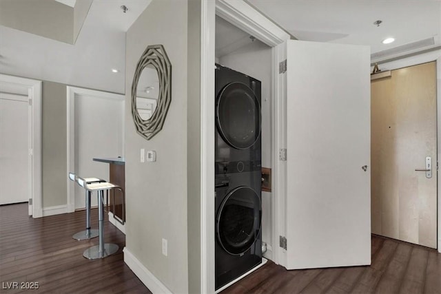 washroom with dark wood-type flooring and stacked washer / drying machine