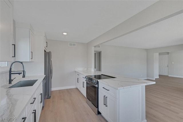 kitchen with stainless steel appliances, light stone countertops, sink, and white cabinets