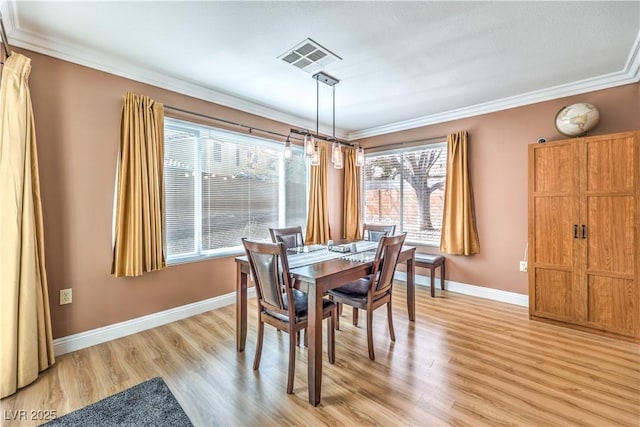 dining space featuring ornamental molding and light hardwood / wood-style flooring