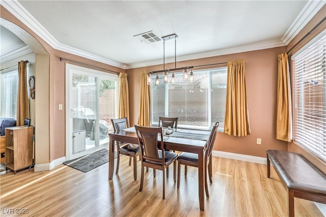 dining room with crown molding and light hardwood / wood-style flooring