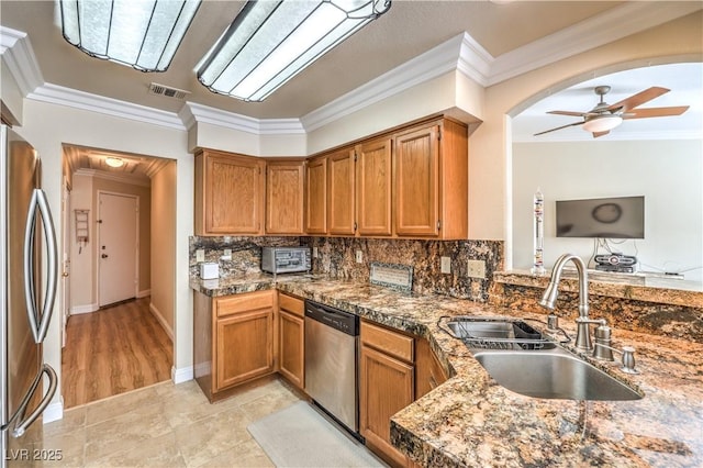 kitchen with sink, crown molding, ceiling fan, stainless steel appliances, and tasteful backsplash