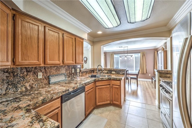 kitchen featuring light tile patterned flooring, sink, hanging light fixtures, ornamental molding, and stainless steel appliances