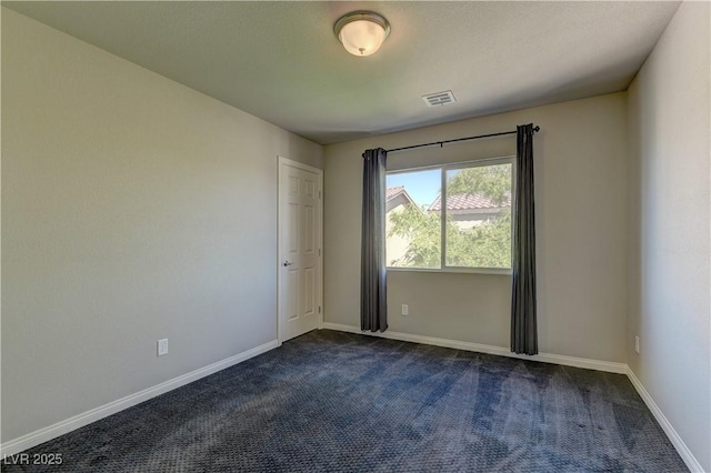 spare room featuring dark carpet