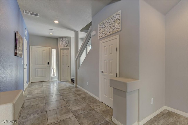 foyer featuring light tile patterned floors and a textured ceiling