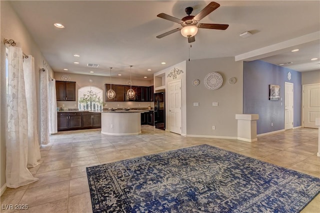 kitchen with dark brown cabinetry, a center island, hanging light fixtures, black refrigerator, and ceiling fan