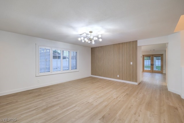 spare room with visible vents, light wood-style flooring, a textured ceiling, french doors, and a chandelier