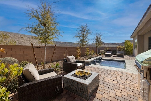 view of patio / terrace featuring a fenced in pool, pool water feature, a mountain view, and an outdoor fire pit