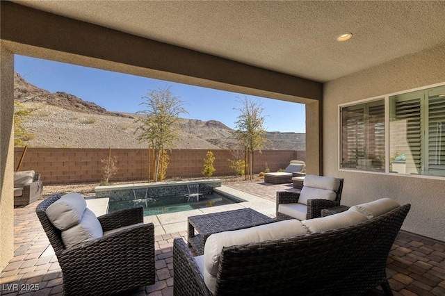 view of patio / terrace with a fenced in pool, pool water feature, outdoor lounge area, and a mountain view