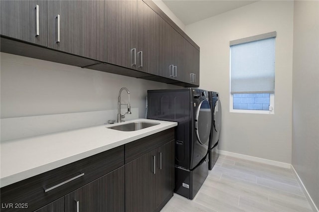 clothes washing area with sink, cabinets, and washing machine and clothes dryer