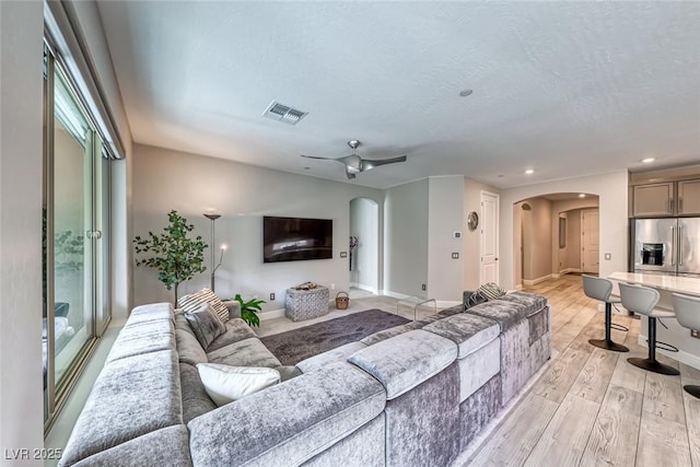 living room with ceiling fan, light hardwood / wood-style flooring, and a textured ceiling