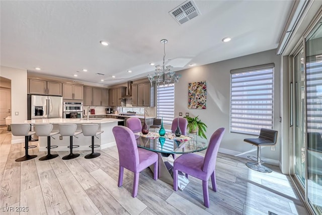 dining space featuring sink, a chandelier, and light hardwood / wood-style flooring