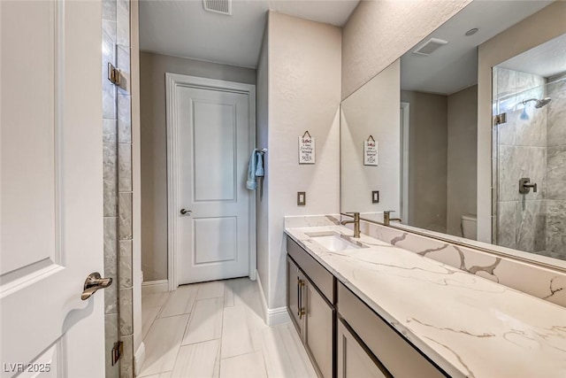 bathroom with vanity, toilet, and tiled shower