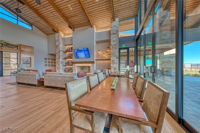 unfurnished dining area featuring beam ceiling, high vaulted ceiling, wood ceiling, and light hardwood / wood-style floors