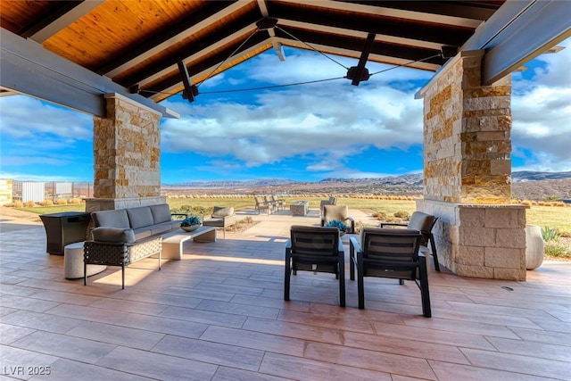 view of patio / terrace with a mountain view and an outdoor living space with a fireplace