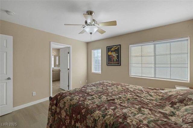 bedroom featuring ceiling fan, light hardwood / wood-style floors, and ensuite bath