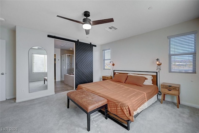 carpeted bedroom with multiple windows, a barn door, ceiling fan, and ensuite bathroom