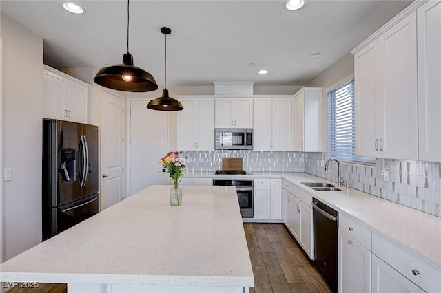 kitchen with sink, white cabinetry, a center island, hanging light fixtures, and appliances with stainless steel finishes