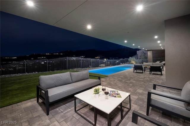 pool at night featuring outdoor lounge area and a patio area