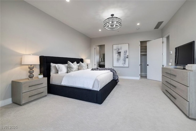 carpeted bedroom with a spacious closet, an inviting chandelier, and ensuite bath