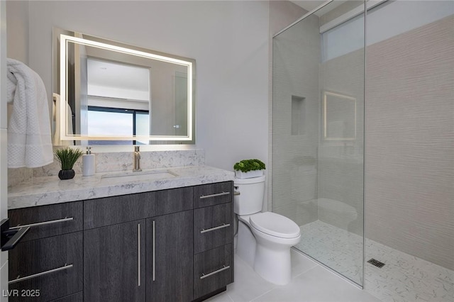 bathroom with tile patterned floors, toilet, vanity, and a tile shower