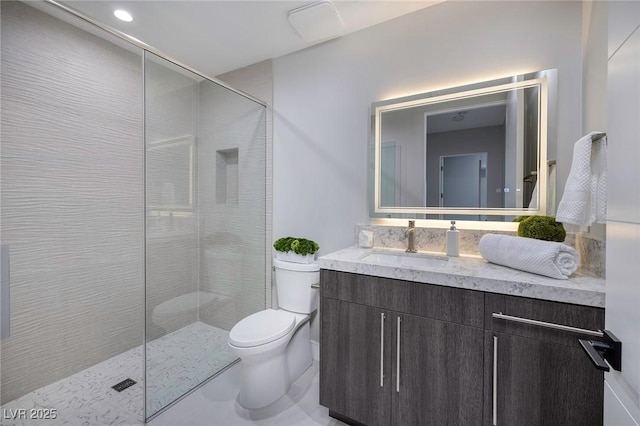 bathroom featuring vanity, toilet, and tiled shower