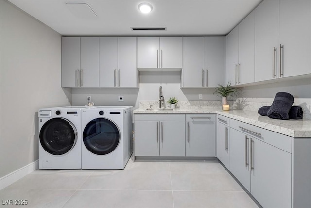 laundry room with cabinets, sink, washer and dryer, and light tile patterned floors