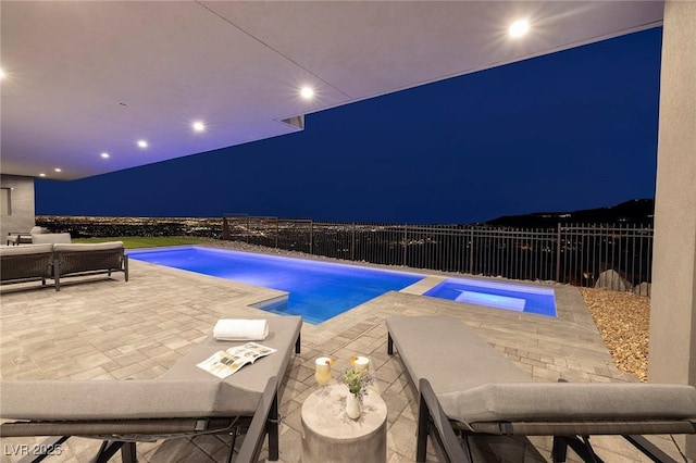 pool at night featuring an in ground hot tub and a patio