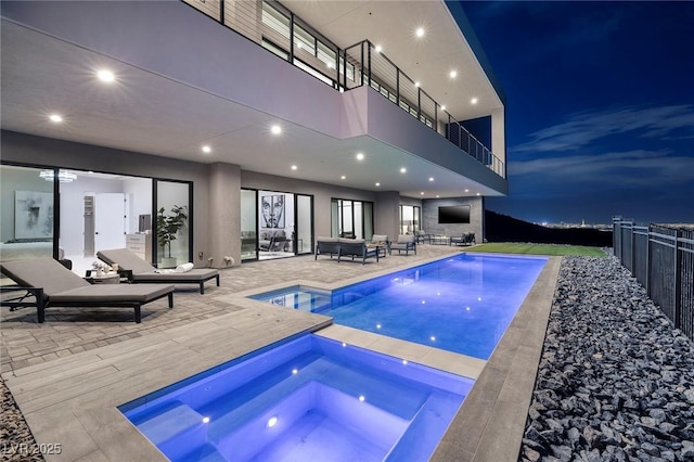 pool at twilight with a patio and an in ground hot tub