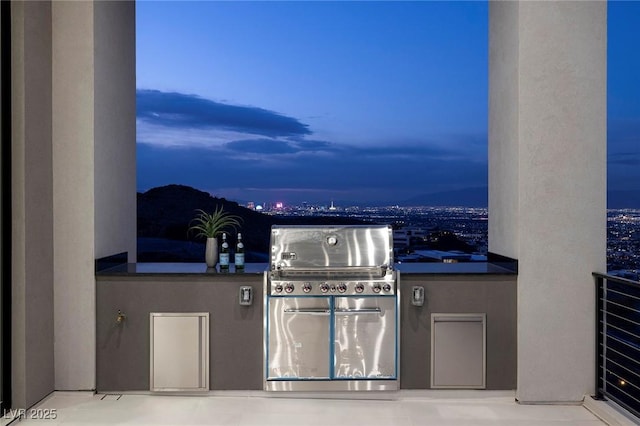 patio terrace at dusk featuring area for grilling and a grill